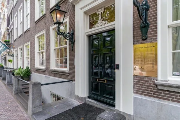 Ingang van een statig herenhuis aan Lange Voorhout 86 met een zwarte voordeur, lantaarns en een naamplaquette.